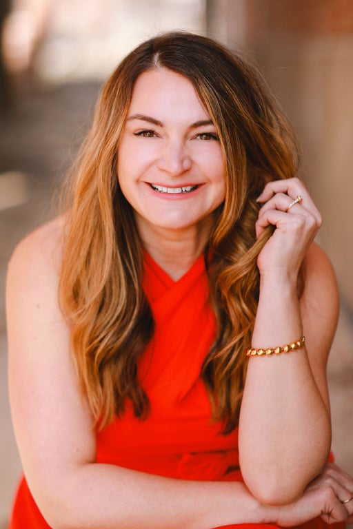 A smiling person in a red dress sitting 